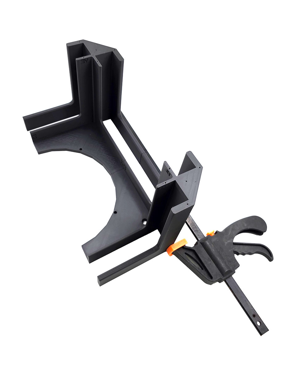 Clamping two glued tower pieces with a bar clamp while the adhesive cures.